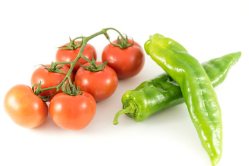 tomato on branch and green peppers on white background