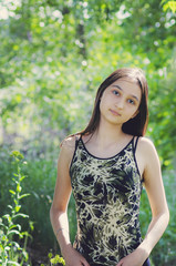 Fototapeta premium Pretty teen girl brunette with long hair on a background of summer nature. Vertical photography.