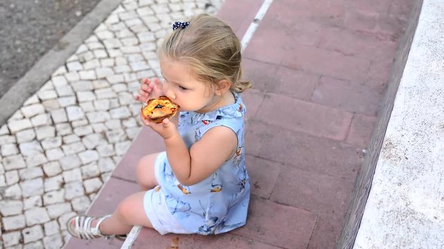 The girl is eating Pasteis de Belem egg tart, typical Portuguese dessert