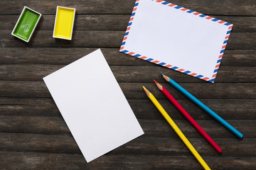 Blank postcard and art supplies flat lay on rustic wooden background. Art supply in summer travel.