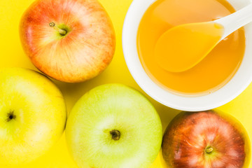 Rosh Hashanah, apples and cup of honey on yellow background. close up