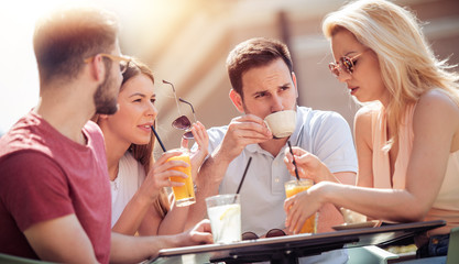 Four laughing friends enjoying coffee in a cafe