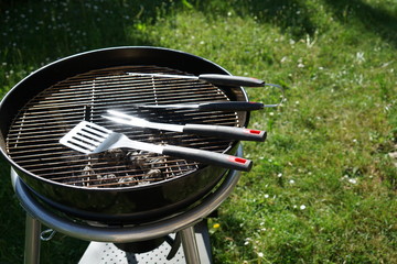 Cutlery for sausages barbecue with a charcoal barbecue in the garden
