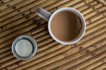Coffee cup with milk on wooden table. Summer travel breakfast. Rustic table top view with coffee drink and milk
