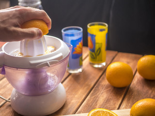 preparation of fresh orange juice smoothie with juicer on a wooden surface