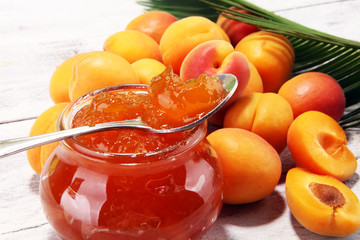 apricot jam and a bunch of fresh apricots on wooden table.