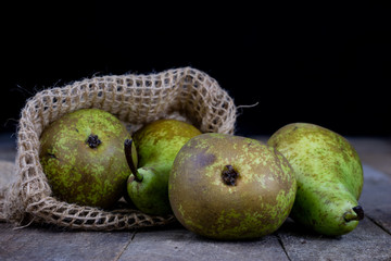 Tasty pears in a jute sack lying on a wooden kitchen table. Fruit for making meals in the kitchen.