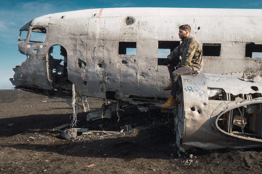 Man sitting on old destroyed airplane