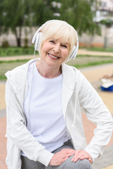 Obraz premium smiling elderly woman listening music in headphones