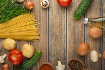 Fresh vegetables and spaghetti, on a wooden texture with an empty space for the inscription.