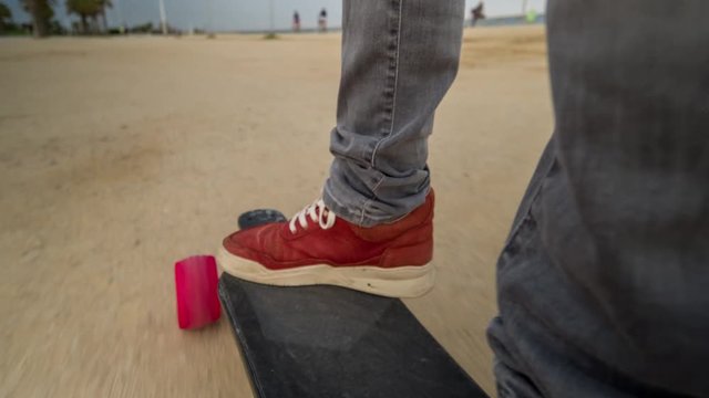 a man's feet on an electric skateboard as it moves along the ground near barcelona beach