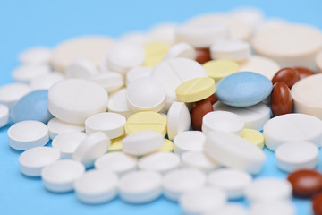 different medicine pills and tablets on blue background