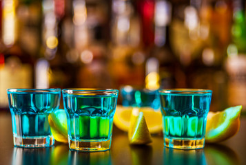 Popular blue drink shot kamikaze on the background of the bar with bottles, a refreshing drink