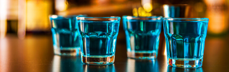 Popular blue drink shot kamikaze on the background of the bar with bottles, a refreshing drink