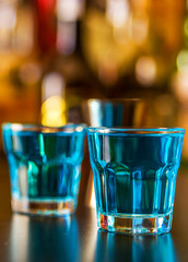 Popular blue drink shot kamikaze on the background of the bar with bottles, a refreshing drink