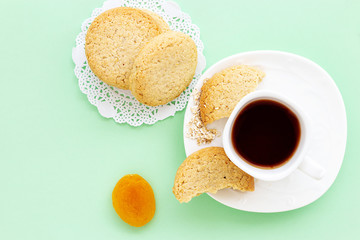 Glutenfree homemade oatmeal cookies and dry apricot and cup of tea or coffee espresso on pastel green background. Mint color background. Top view.