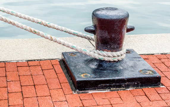black iron ship's bollard with mooring lines on a red brick wharf at Baltimore's Inner Harbor