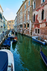 Fototapeta na wymiar Traditional narrow canal with gondolas and boats in Venice, Italy. Summer