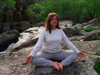 Woman meditating in a river waterfall