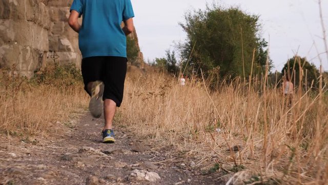 Young man in sportswear running along ancient roman aqueduct Appio Claudio. Training outdoor alone in peaceful park in Rome at sunset slow motion.