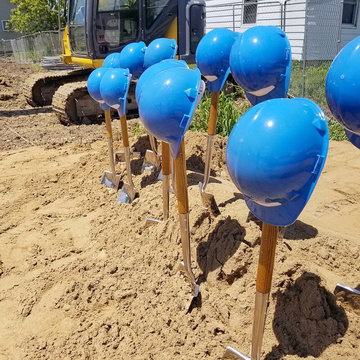 blue hard hats on new shovels for ground breaking ceremony