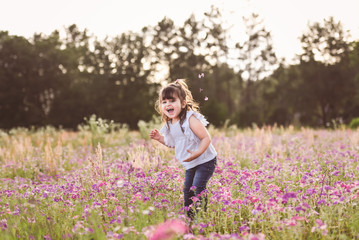 Obraz na płótnie Canvas Little girl in a purple flower field during the evening golden light in the summer