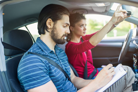 Driving school or test. Beautiful young woman learning how to drive car together with her instructor.
