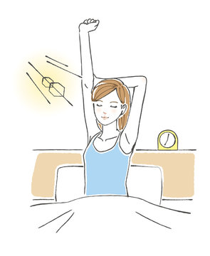 ベッドの上で背伸びをする女性 朝