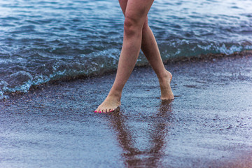 The girl is walking along the seashore, beautiful legs