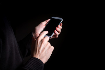 Man's hands using a smartphone on a black background