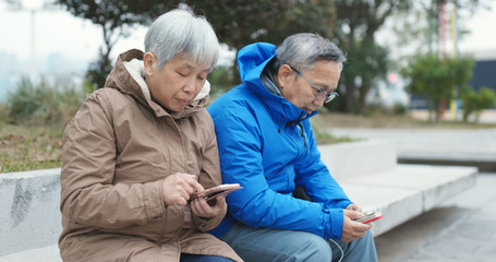 Senior couple using cellphone together at street