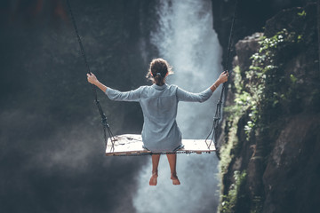 Beautiful woman swings near waterfall in the jungle of Bali island, Indonesia.