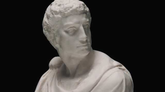 Old roman era white marble sculpture of Brutus bust with a slow camera vertical pan to reveal the art piece.