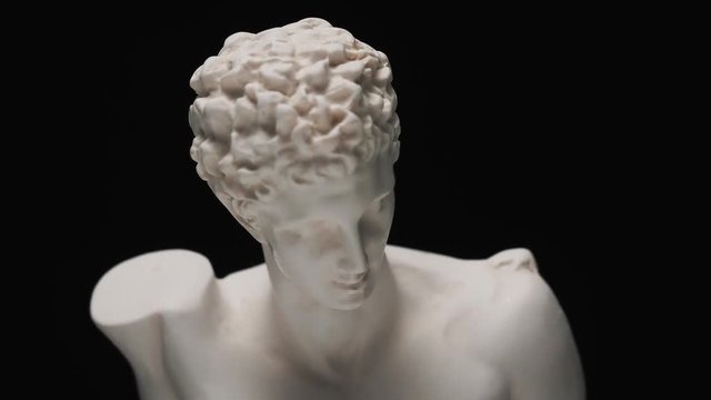 Old roman era white marble sculpture of Hermes bust with a slow camera vertical pan to reveal the art piece.