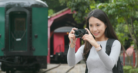 Woman travel and taking photo on digital camera at train station