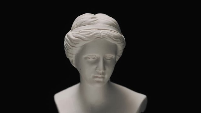 Old roman era white marble sculpture of Venus bust with a slow camera vertical pan to reveal the art piece.