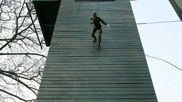 Soldiers practice abseiling down a wooden platform. Group of chinese soldiers abseiling face first down fast. Anti terrorist training.