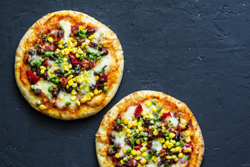 Mexican vegetarian pizza with beans, corn, jalapeno pepper, mozzarella cheese on a dark background,...