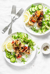Grilled chili honey lime chicken skewers with rice and avocado salsa on light background, top view. Flat lay