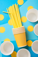 Yellow straws for a party in paper cups on a bright background