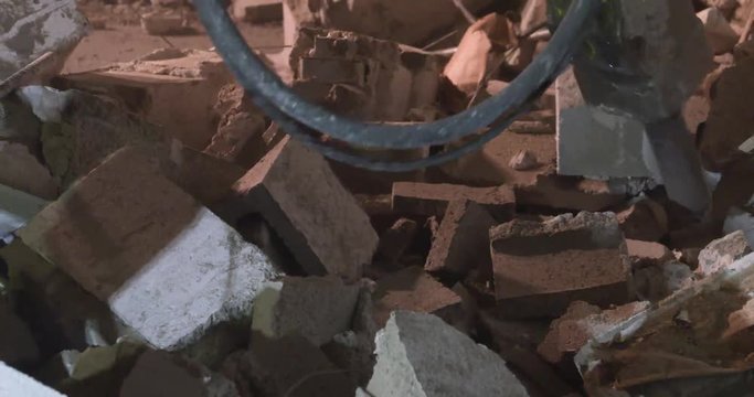 A jackhammer demolishes a cinderblock wall.