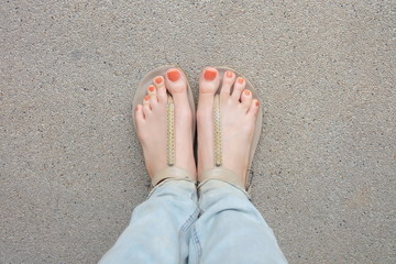 Beautiful Orange Nails Polish. Woman Slime Legs and Feet Wearing Lack of Blue Jeans and Nude...