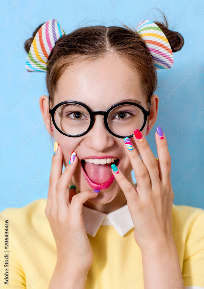 Wall mural a young beautiful girl with a funny hairstyle wearing glasses is holding hands with a bright manicur