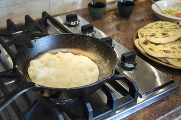 Homemade Naan bread being cooked on the stove top