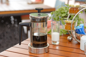 Black coffee in French press coffee with milk on wooden table for breakfast