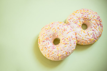Assorted donuts isolated. Tasty donuts with colorful sprinkles on light soft green background. Sweet and colorful dessert. Copy space