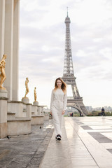 Young woman walking on Trocadero square near gilded statues and Eiffel Tower in Paris. Concept of...