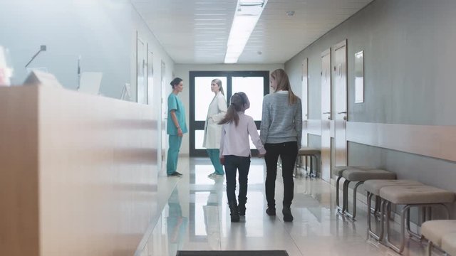 In the Hopistal Hallway Nurses and Doctors Stand Talking and Mother and Child Walk through the Corridor. New Modern Medical Facility. Shot on RED EPIC-W 8K Helium Cinema Camera.