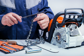 Professional technician working in repair service. Repairing chainsaw on workbench.