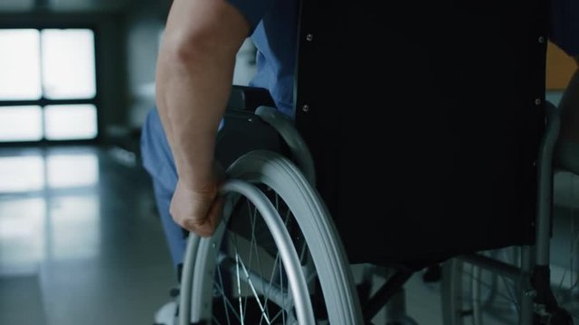 In the Hospital, Close-up Following Shot of the Elderly Man in the Wheelchair Moving through the Hallway. Shot on RED EPIC-W 8K Helium Cinema Camera.